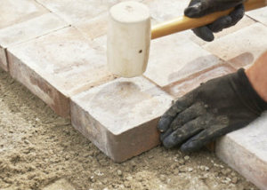 katy paver contractor pounding in brinks with wood hammer